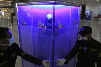 A woman stands inside a sterilization chamber set up at the arrival hall of Juanda International Airport amid new coronavirus outbreak, in Surabaya, Indonesia, March 24, 2020. (AP Photo)