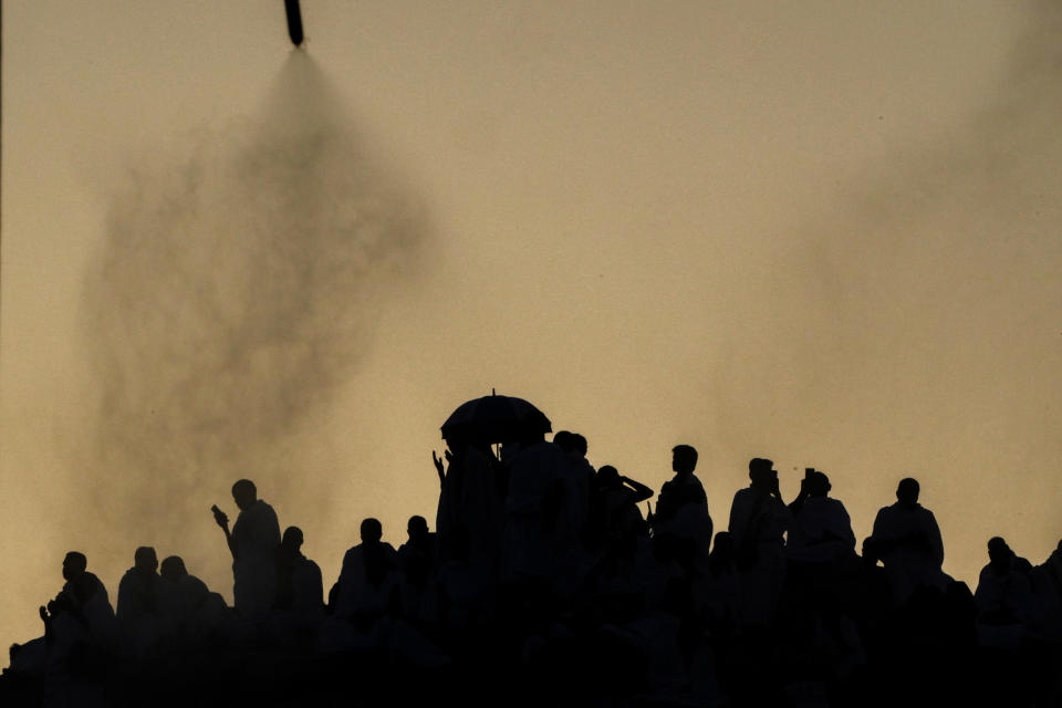Water mist is sprayed on Muslim pilgrims as they pray on the rocky hill known as the Mountain of Mercy, on the Plain of Arafat, during the annual Hajj pilgrimage, near the holy city of Mecca, Saudi Arabia, Tuesday, June 27, 2023. Around two million pilgrims are converging on Saudi Arabia's holy city of Mecca for the largest Hajj since the coronavirus pandemic severely curtailed access to one of Islam's five pillars. (AP Photo/Amr Nabil)