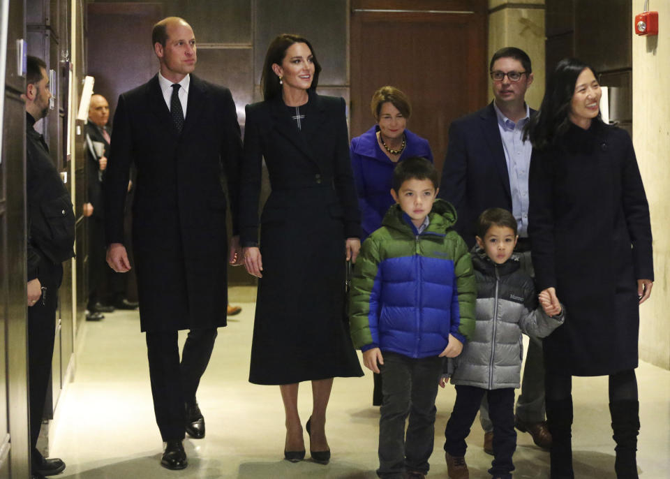 Boston Mayor Michelle Wu, right, husband Conor Perwarski and sons Blaise, second right, and Cass, show photos of the Queen Elizabeth II's visit in 1976, during the visit of Britain's Prince William and Kate, Princess of Wales, to Boston City Hall on Wednesday, Nov. 30, 2022, in Boston. The Prince and Princess of Wales are making their first overseas trip since the death of Queen Elizabeth II in September. (Nancy Lane/The Boston Herald via AP, Pool)