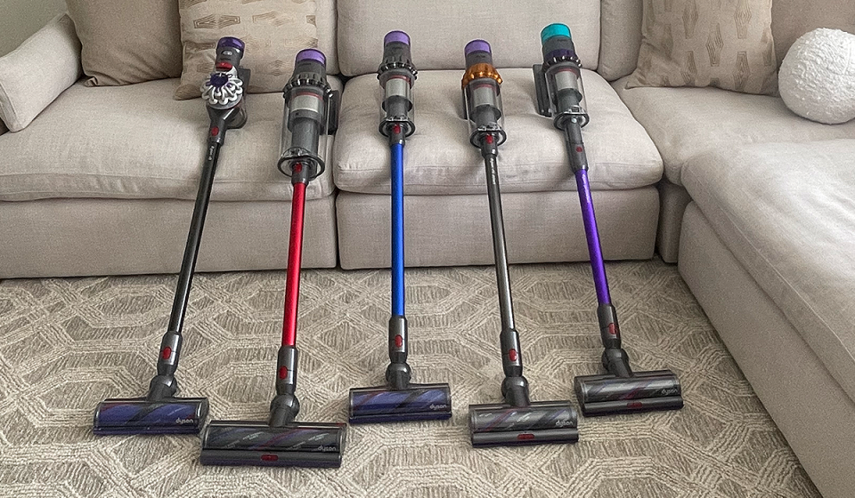 Dyson stick vacuums are shown lined up in a row for Yahoo Life's Best Dyson cordless stick vacuums guide.