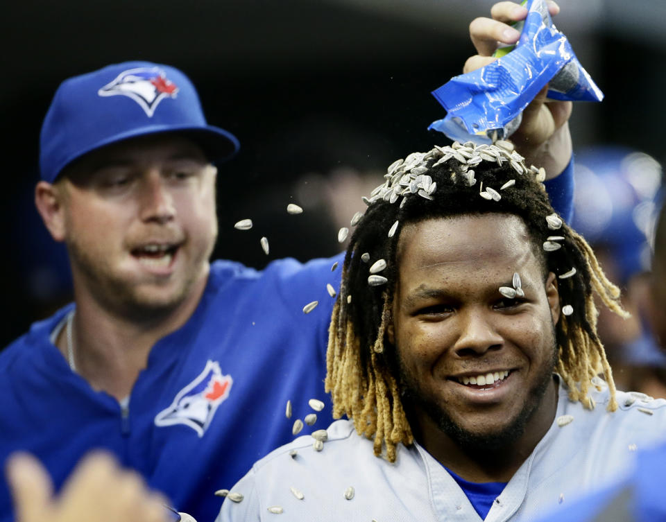 Vladimir Guerrero Jr. recibe un baño de semillas de Justin Smoak (izquierda) tras batear un grand slam ante los Tigres de Detroit, el sábado 20 de julio de 2019. (AP Foto/Duane Burleson)