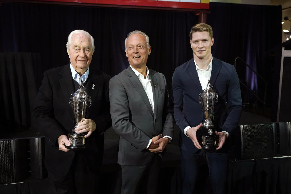 Fred Lissalde, center, president and CEO of BorgWarner; Roger Penske, team owner, left, and driver Josef Newgarden, right, winner of the 2023 Indianapolis 500, hold their Baby Borg driver's and team owner's trophies, Tuesday, Jan. 23, 2024 in Dearborn, Mich. (AP Photo/Carlos Osorio)