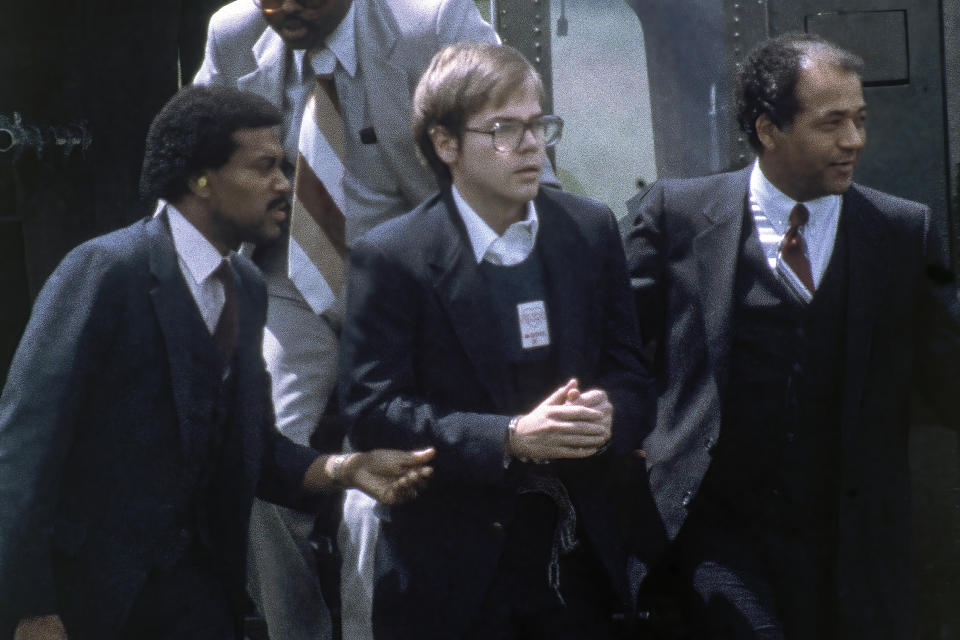 FILE - U.S. Marshals escort John Hinckley Jr. as he returns to a marine base via helicopter in Quantico, Va., Aug. 8, 1981. Hinckley, who shot and wounded President Ronald Reagan in 1981, was freed from court oversight Wednesday, June 15, 2022, officially concluding decades of supervision by legal and mental health professionals. (AP Photo/Barry Thumma, File)