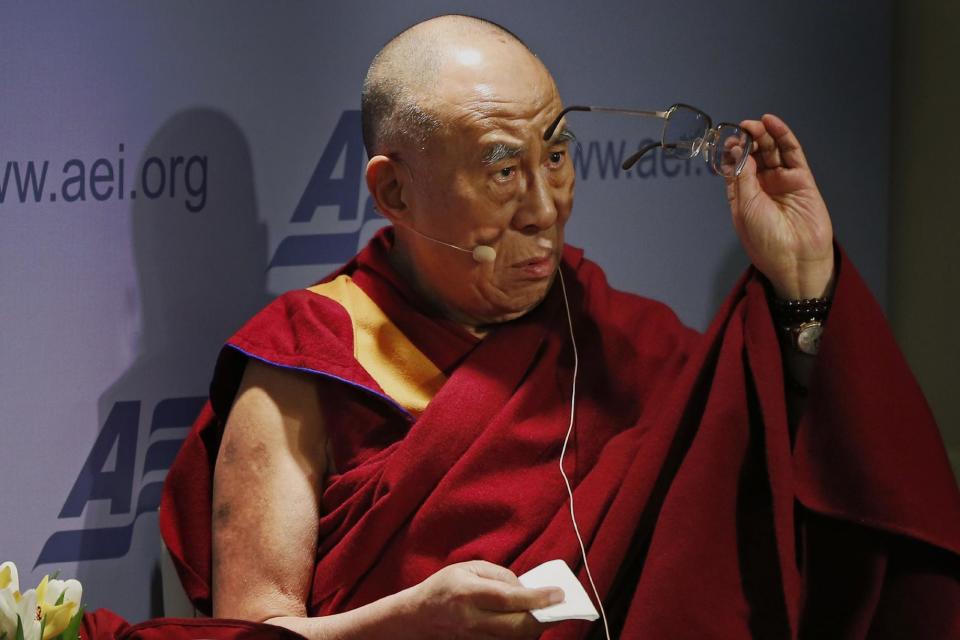 Tibetan spiritual leader the Dalai Lama cleans his glasses before speaking at an event entitled: "Happiness, Free Enterprise, and Human Flourishing" Thursday, Feb. 20, 2014, at the American Enterprise Institute in Washington. (AP Photo/Charles Dharapak)