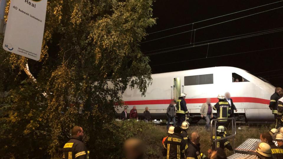 Rettungskräfte helfen Bahn-Passagieren bei ihrem Weg aus dem liegengebliebenen ICE 1272 zu einer Bushaltestelle. Foto: Horstmann