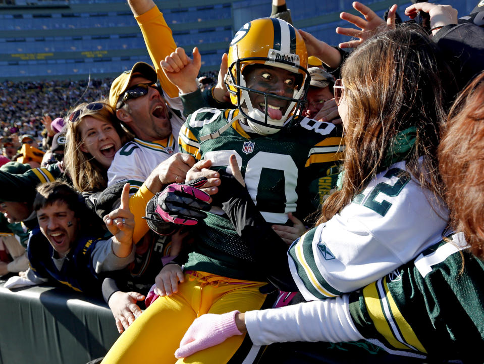 FILE - In this Oct. 28, 2012, file photo, Green Bay Packers wide receiver Donald Driver celebrates a touchdown after doing a Lambeau Leap during the second half of an NFL football game against the Jacksonville Jaguars, in Green Bay, Wisc. As lock-downs are lifted, restrictions on social gatherings eased and life begins to resemble some sense, sports are finally starting to emerge from the coronavirus pandemic. Many sports business experts believe those hardy fans will be the first to return. (AP Photo/Mike Roemer, File)