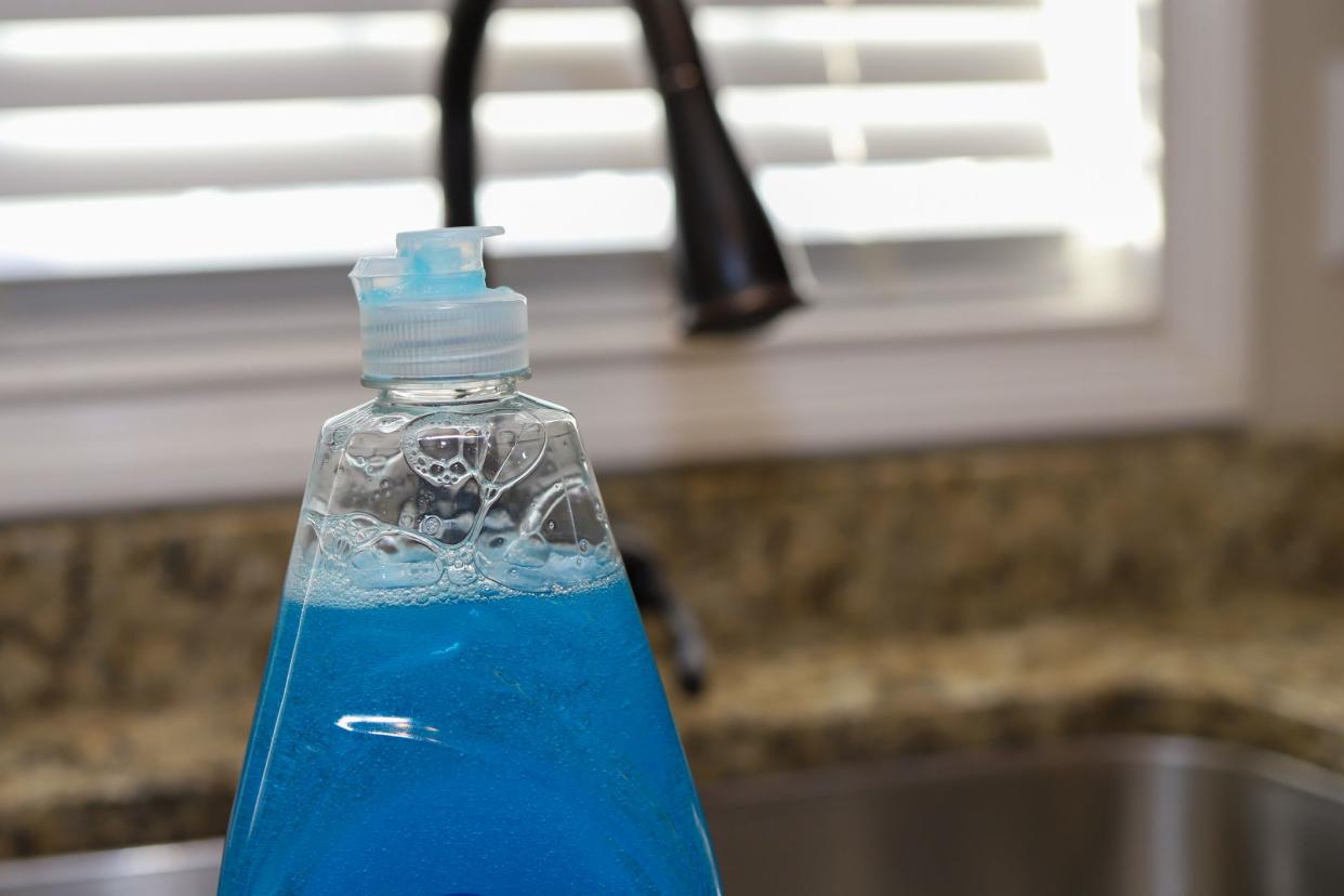 A bottle of  dish detergent sitting on a kitchen sink