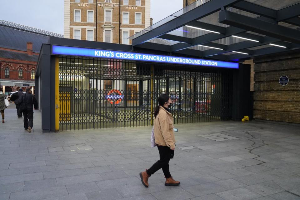 A woman walks past the closed shutters at the entrance to King’s Cross station (Stefan Rousseau/PA) (PA Wire)