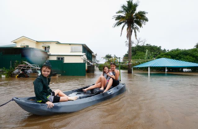 Keara, Lacey and Erich Stewart paddle in a kayak after flood waters entered their back yard in Murwillumbah. Picture: Getty