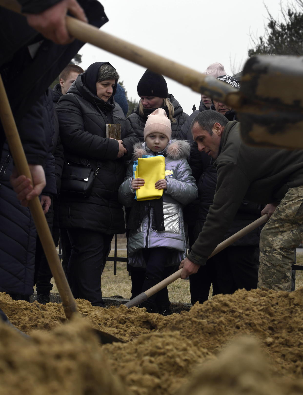 A child looks on as the burial service takes place at a local cemetery.