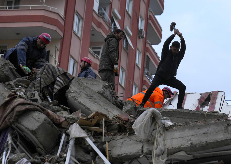 Emergency team members and others search for people in a destroyed building in Adana, Turkey.