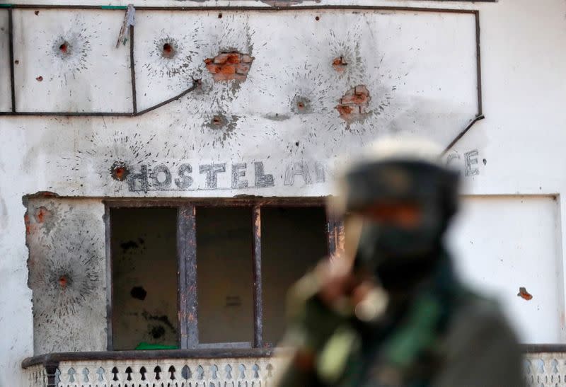 Bullet holes are seen on the wall of a house next to a soldier standing guard, after a gun battle between Indian army soldiers and suspected militants in Hokarsar