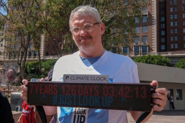 Adam McKay holds a Climate Clock during a rally in Los Angeles in 2022. - Credit:  Ringo Chiu/AFP/Getty Images