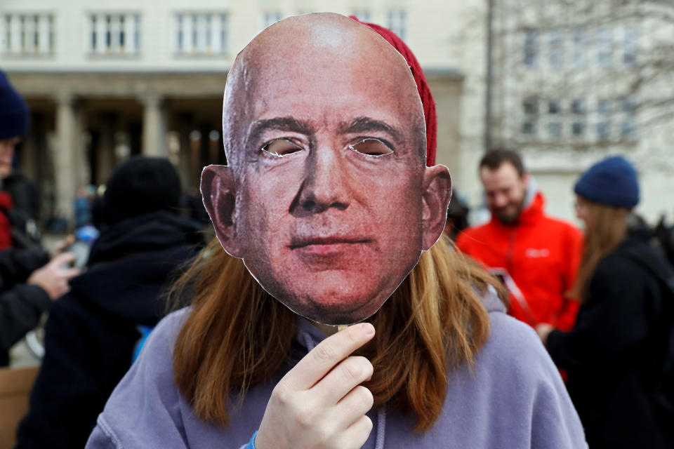 An activist holds up a mask depicting Amazon founder Jeff Bezos, during a protest against the opening of a new Amazon office in Berlin, Germany, February 22, 2020. REUTERS/Michele Tantussi