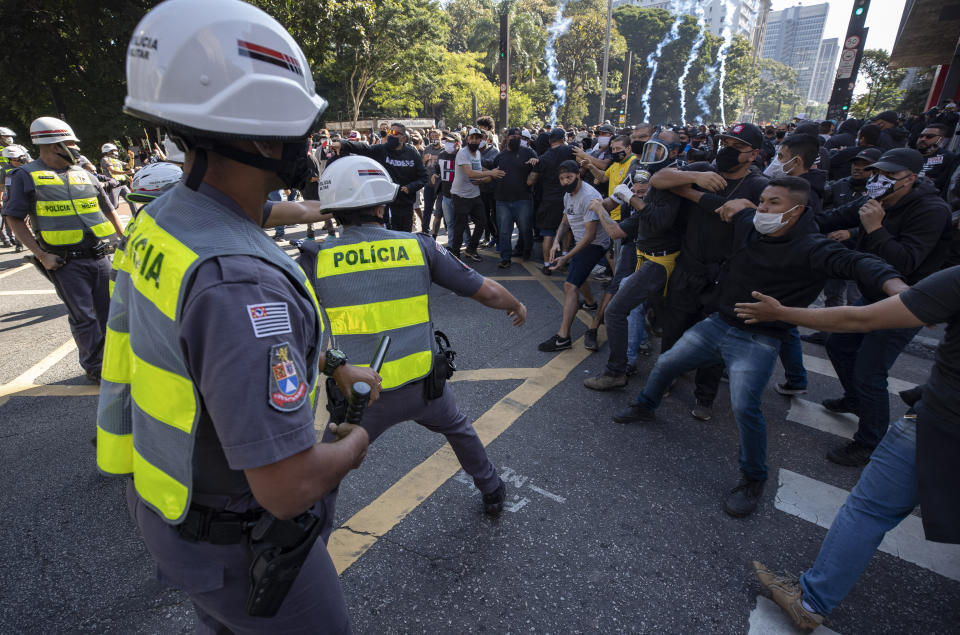 Police clash with demonstrators during a protest against fascism, President Jair Bolsonaro and to defend democracy in Sao Paulo, Brazil, Sunday, May 31, 2020. Police used tear gas to disperse anti-government protesters in Brazil's largest city as they began to clash with small groups of demonstrators loyal to President Jair Bolsonaro. (AP Photo/Andre Penner)