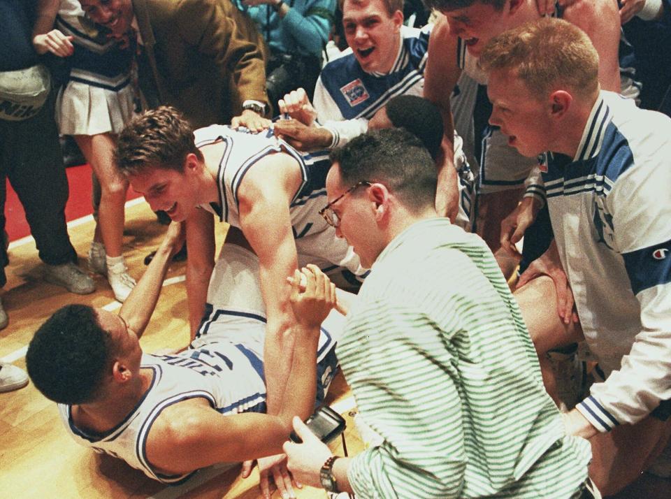 FILE - Duke's Christian Laettner, top, who scored the game-winning basket in overtime, celebrates with teammate Grant Hill on the floor of the Philadelphia Spectrum as teammates and fans crowd around, March 28, 1992. Defending champion Duke beat Kentucky 104-103 to advance to the Final Four. (AP Photo/Amy Sancetta, FIle)