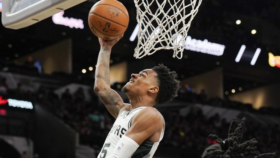 Dejounte Murray’s knee buckled as he drove to the lane against the Houston Rockets’ James Harden in a game Sunday.