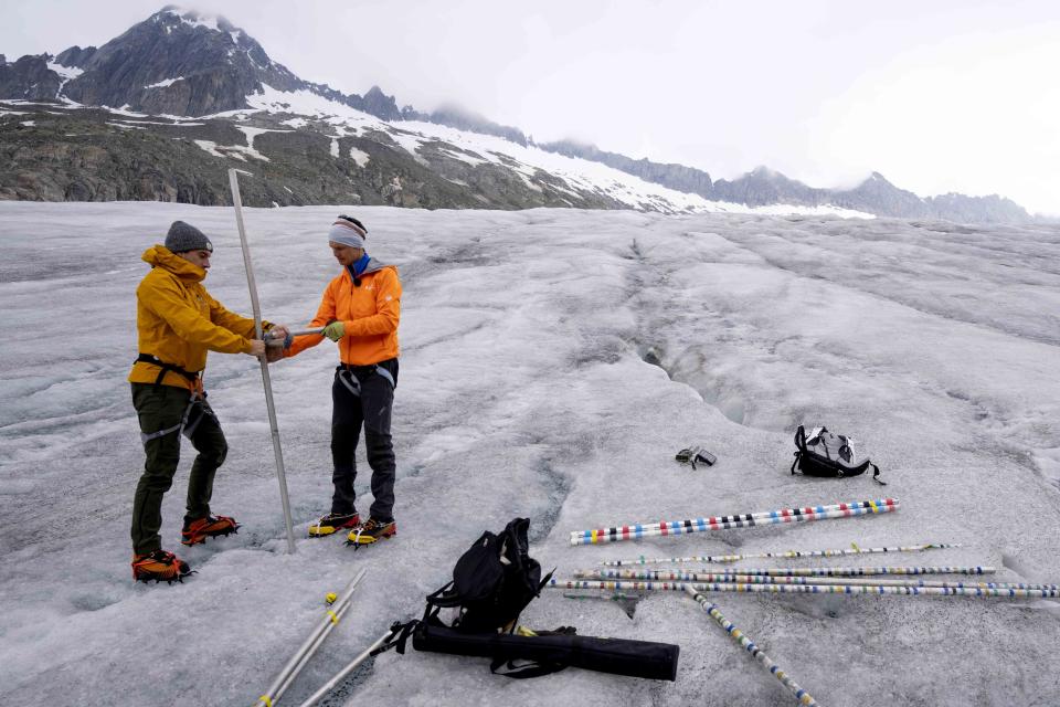 Swiss Federal Institute of Technology glaciologist and head of the Swiss measurement network 'Glamos', Matthias Huss, right, and an assistant prepare a camera at the Rhone Glacier near Goms, Switzerland, Friday, June 16, 2023. Now dwindling at an alarming rate because of human-caused climate change, the group monitors what is left of the country's glaciers in an attempt to slow their demise. (AP Photo/Matthias Schrader)