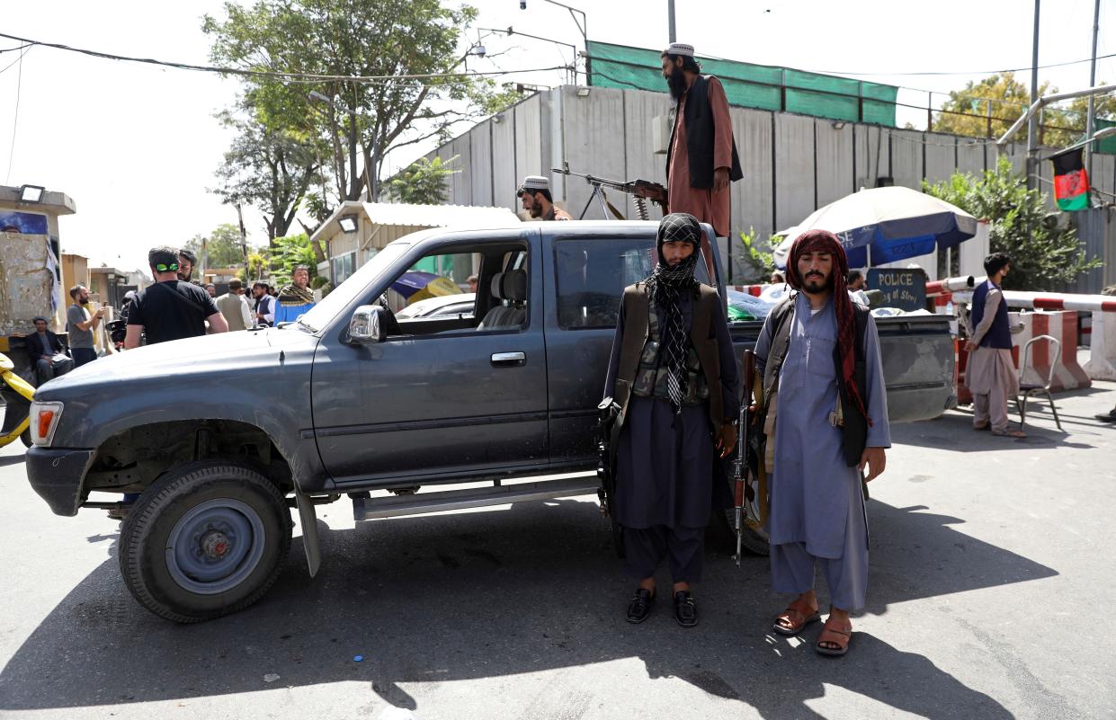 Taliban fighters stand guard in front of the main gate leading to the Afghan presidential palace in Kabul, Afghanistan on Monday, Aug. 16, 2021. The U.S. military struggled to manage a chaotic evacuation from Afghanistan on Monday as the Taliban patrolled the capital and tried to project calm after toppling the Western-backed government.