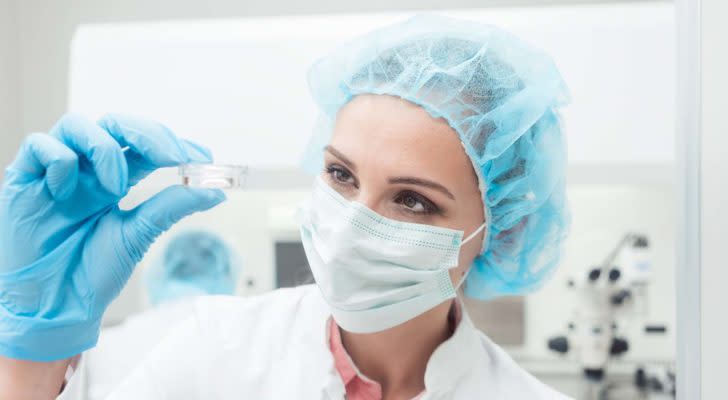 A scientist holding up her biotech experiment in a small Petri dish.