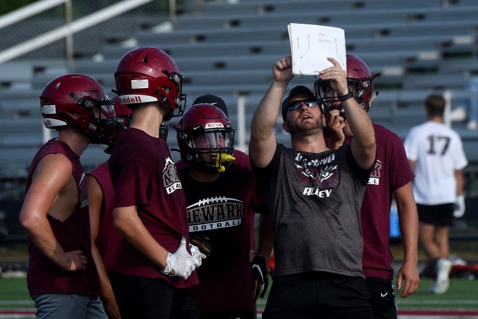 Newark assistant coach Tanner Taylor goes through the next play with the offense during a 7-on-7 scrimmage with Johnstown last month at White Field.