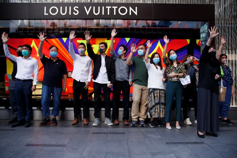 Office workers shout slogans as they attend a lunchtime anti-government protest in the Central district of Hong Kong