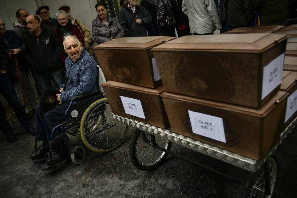 Valeriano Rebolledo, 91 years old, whose father Carlos Rebolledo was killed in 1937, looks at some of the 46 coffins of unidentified people killed during the Spanish Civil War, at San Jose cemetery, Pamplona, northern Spain, Monday, April 1, 2019. Marking eight decades since the end of the Spanish Civil War, the remains of 46 unidentified victims of the conflict have been reburied in the northern city of Pamplona. More than half a million people died in the 1936-1939 war between rebel nationalist forces led by Gen. Francisco Franco and defenders of the short-lived Spanish republic. (AP Photo/Alvaro Barrientos)