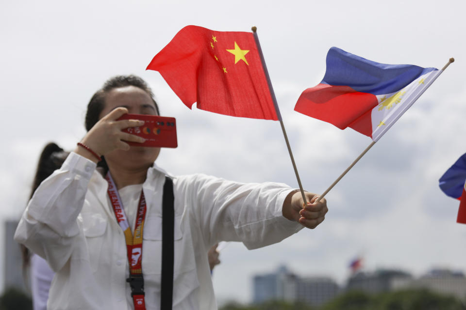 A Chinese visitor takes a picture of flags during the arrival of Chinese naval training ship, Qi Jiguang, for a goodwill visit at Manila's port, Philippines Wednesday, June 14, 2023. The Chinese navy training ship made a port call in the Philippines on Wednesday, its final stop on a goodwill tour of four countries as Beijing looks to mend fences in the region. (AP Photo/Basilio Sepe)