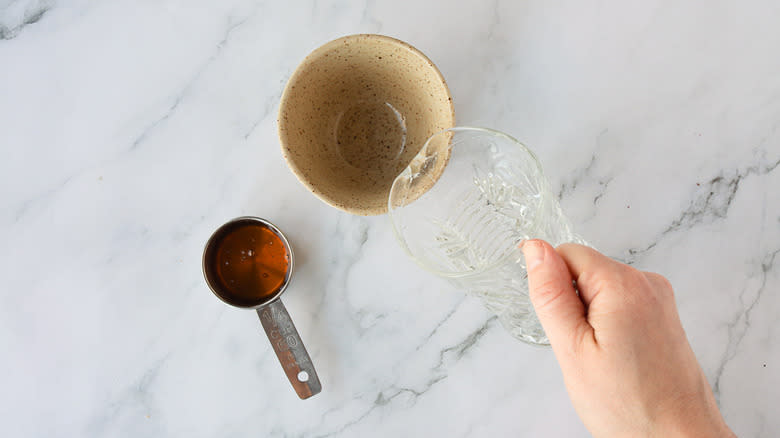 Adding water to bowl besides spoon with honey