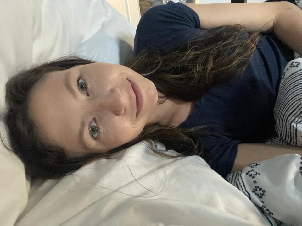 Samantha Brandon lying down in bed looking at camera