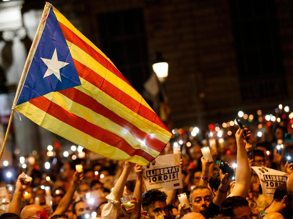 People hold candles and a Catalan pro-independence 'Estelada' flag during a demonstration in Barcelona against the arrest of two Catalan separatist leaders: PAU BARRENA/AFP/Getty Images