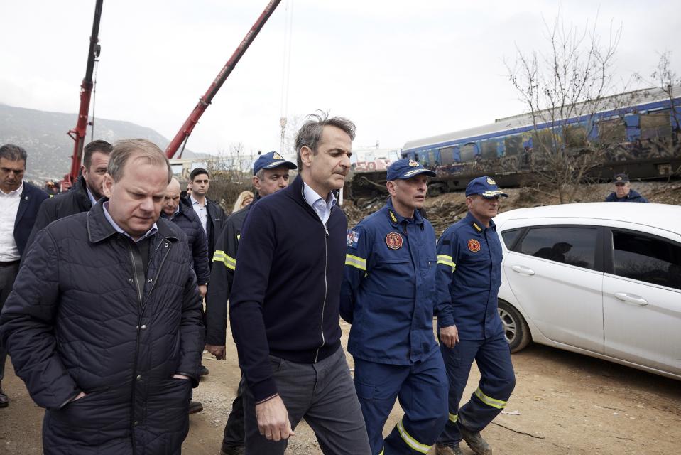FILE - Greece's Prime Minister Kyriakos Mitsotakis, second left, accompanied by Transport Minister Kostas Karamanlis, left, visit the location of train collision in Tempe, about 376 kilometres (235 miles) north of Athens, near Larissa city, Greece, on March 1, 2023. Prime Minister Kyriakos Mitsotakis has apologized for any responsibility Greece’s government bears for the deadliest train crash in the country’s history. At least 57 people died when a passenger train and a freight train collided late Tuesday. (Dimitris Papamitsos/Greek Prime Minister's Office via AP, File)