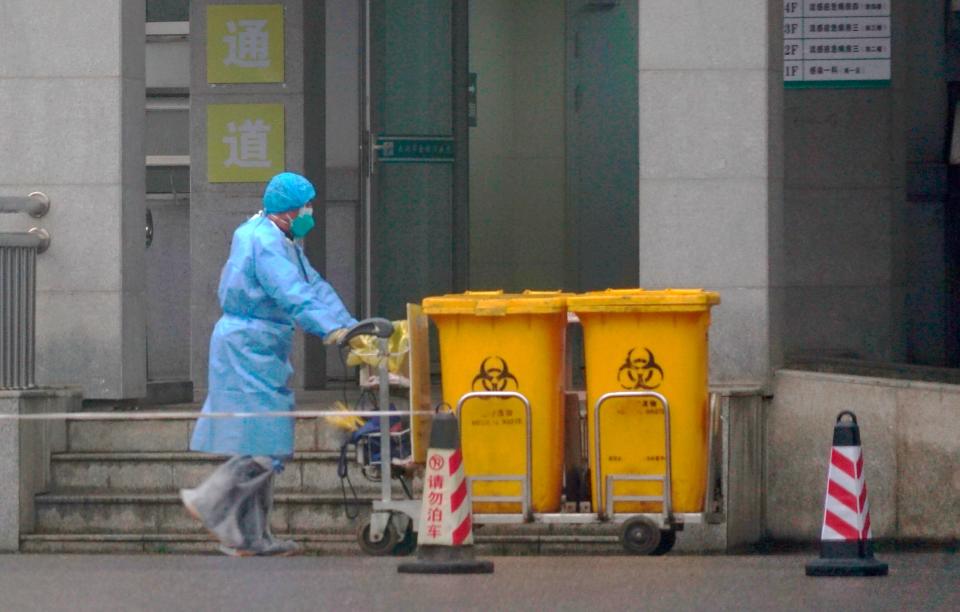 FILE - In this Wednesday, Jan. 22, 2020, file photo, a staff member moves bio-waste containers past the entrance of the Wuhan Medical Treatment Center in Wuhan, China, where some people infected with a new virus are being treated. The new virus comes from a large family of coronaviruses, some causing nothing worse than a cold. Others named SARS and MERS have killed hundreds in separate outbreaks. (AP Photo/Dake Kang, File)
