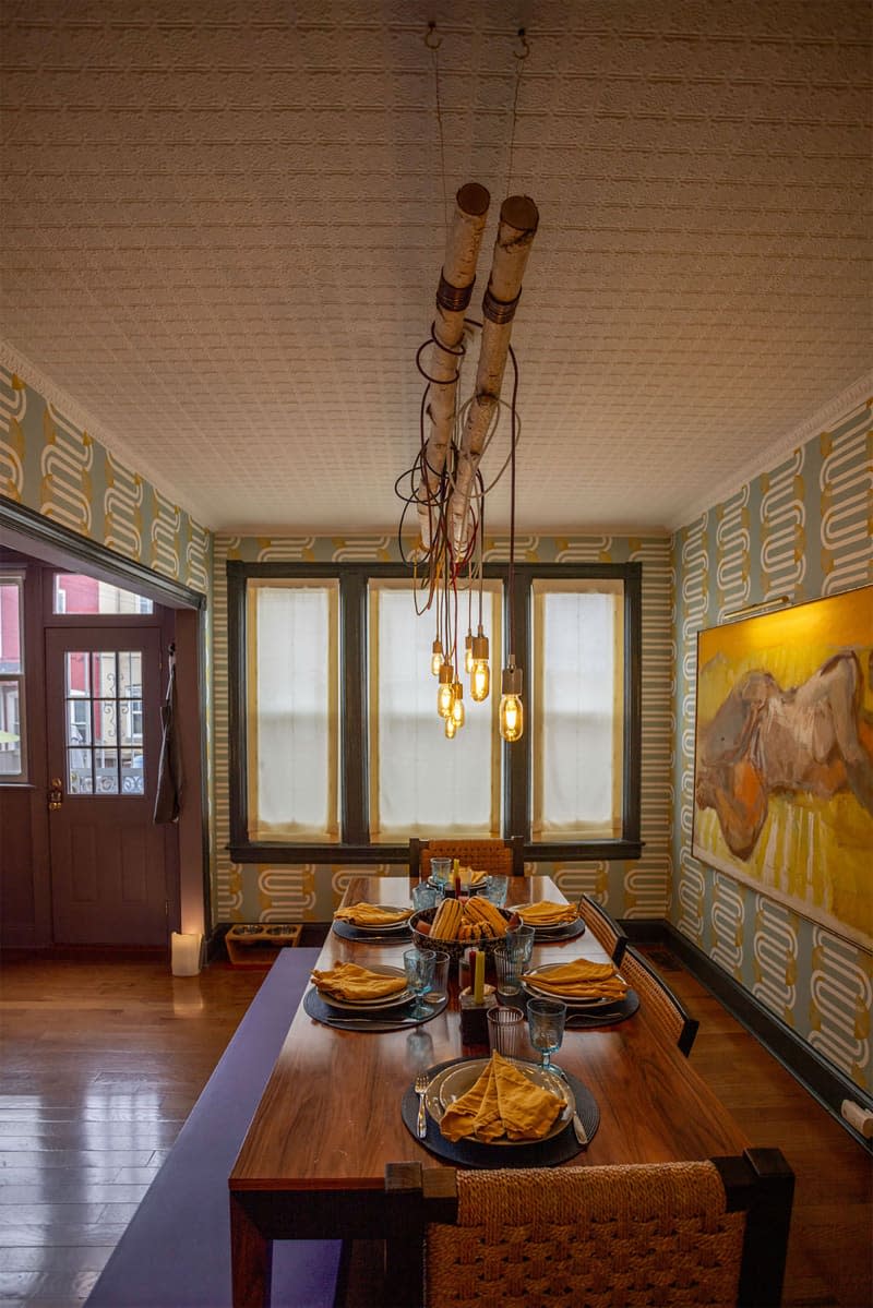 Cord pendants hung above dining table in wallpapered dining room.