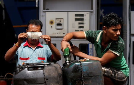 A worker checks a 500 Indian rupee note as a man fills diesel in containers at a fuel station in Kolkata, India, August 14, 2018. REUTERS/Rupak De Chowdhuri