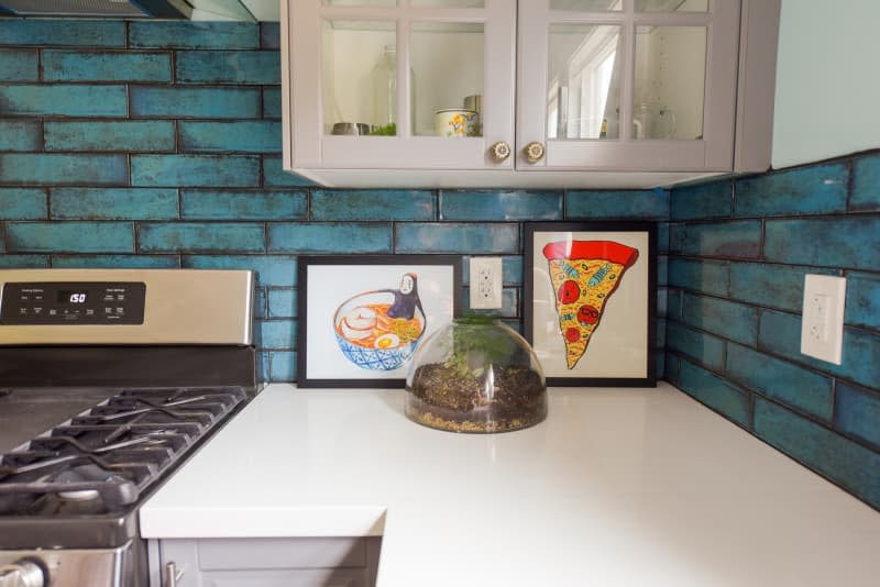 Light blue kitchen with grey cabinets, white countertop and stainless steel appliances.