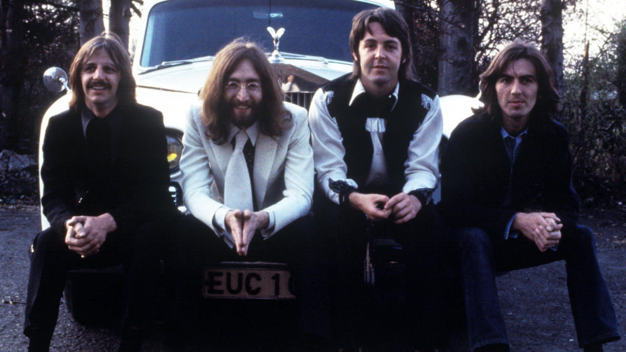  The Beatles sit on a white Rolls Royce. 