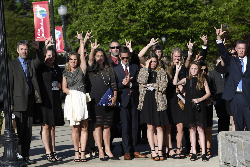 Natalie Henry-Howell, fourth from left, Thomas Howell, parents of Riley Howell, and Lauren Westmoreland, sixth from left, join with others to raise their hands to sign the words, I love you as Riley's casket is placed in a hearse after a memorial service for Riley Howell in Lake Junaluska, N.C., Sunday, May 5, 2019. Family and hundreds of friends and neighbors are remembering Howell, a North Carolina college student credited with saving classmates' lives by rushing a gunman firing inside their lecture hall. (AP Photo/Kathy Kmonicek)