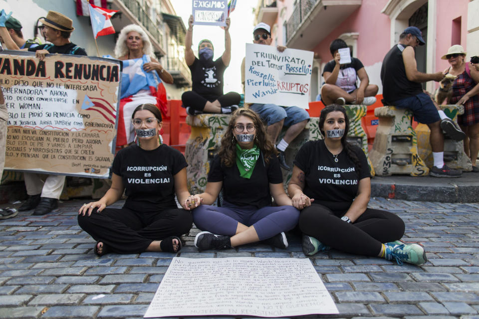 Tres mujeres protestan con otros manifestantes afuera de La Fortaleza, la mansi&oacute;n del gobernador, en San Juan el 9 de agosto, 2019. (Photo: ASSOCIATED PRESS)