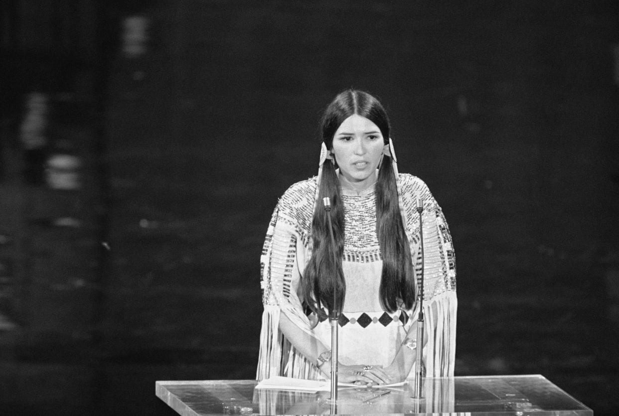 Sacheen Littlefeather addressing the 45th Academy Awards in October 1973, declining Marlon Brando's Oscar for best actor on his behalf. She wore a buckskin dress and moccasins. / Credit: Bettmann via Getty Images