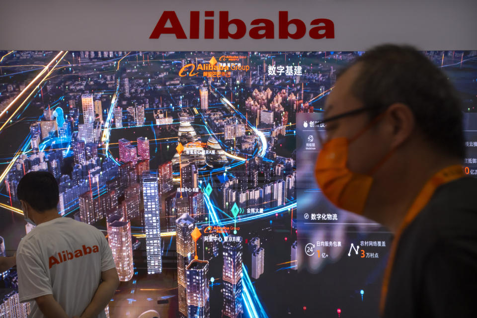 Visitors and staff members walk past an electronic display at a booth for Chinese technology firm Alibaba at the China International Fair for Trade in Services (CIFTIS) in Beijing, Friday, Sept. 3, 2021. E-commerce giant Alibaba Group said Friday it will spend $15.5 billion to support President Xi Jinping's campaign to spread China's prosperity more evenly, adding to pledges by tech companies that are under pressure to pay for the ruling Communist Party's political initiatives. (AP Photo/Mark Schiefelbein)