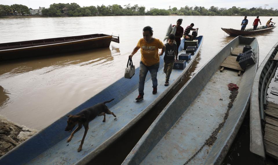 Venezuelans carry their belongings after using a boat to cross the Arauca River, the natural border between Venezuela and Colombia, as they arrive to Arauquita, Colombia, Thursday, March 25, 2021. Thousands of Venezuelans are seeking shelter in Colombia this week following clashes between Venezuela's military and a Colombian armed group in a community along the nations' shared border. (AP Photo/Fernando Vergara)