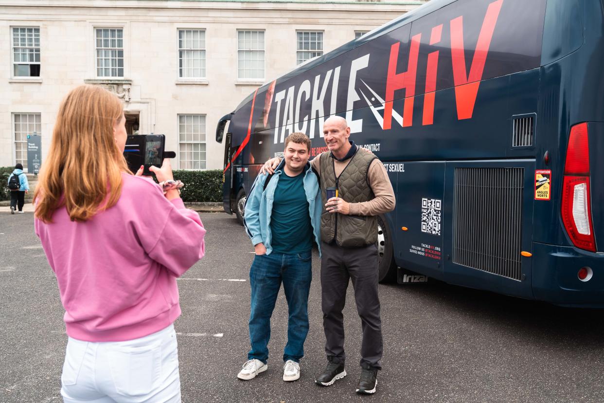 Gareth Thomas posing with a University of Nottingham student in front of the Tackle HIV campaign Myth Tour Bus