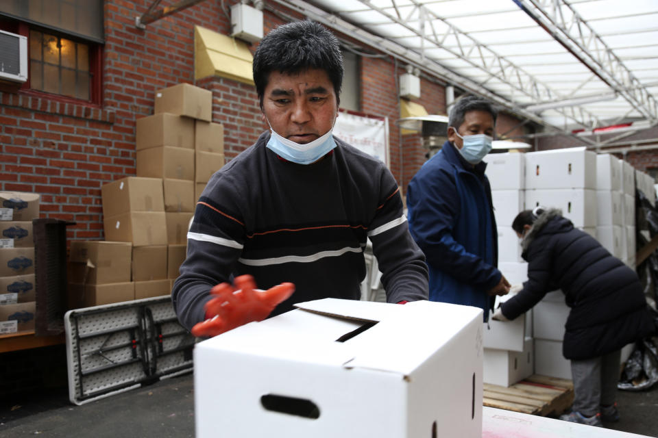 Phurba Sherpa, left, and other volunteers move boxes of food at the United Sherpa Association's weekly food pantry on Friday, Jan. 15, 2021, in the Queens borough of New York. The pantry began in April with a focus on the Nepalese community, international students and families living in the country without permission. (AP Photo/Jessie Wardarski)