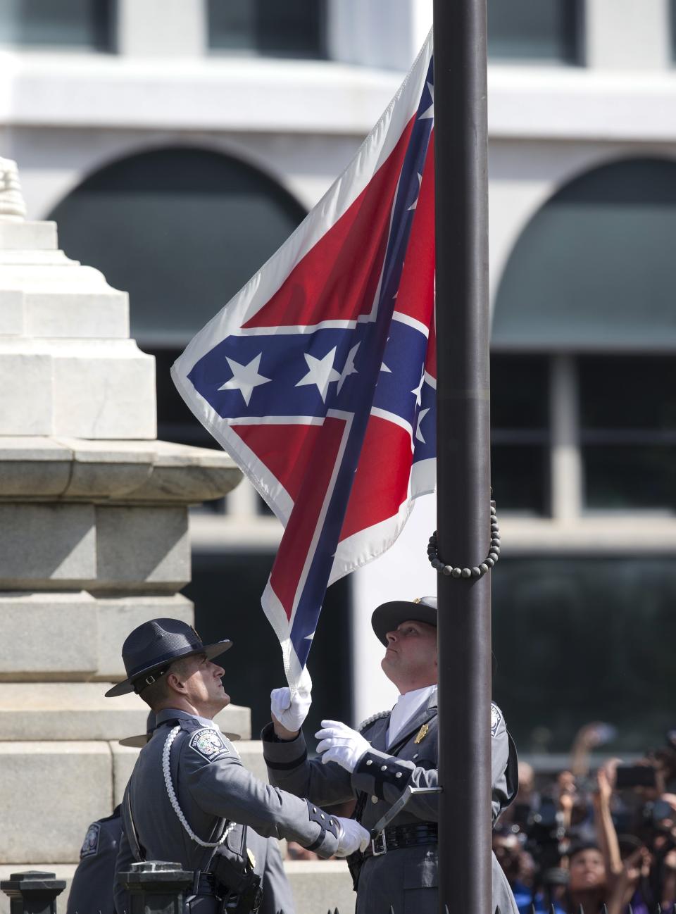 FILE - In a Friday, July 10, 2015 file photo, an honor guard from the South Carolina Highway patrol removes the Confederate battle flag from the Capitol grounds in Columbia, S.C., ending its presence there. One big change happened in conservative South Carolina after a racist gunman killed nine black people during a Bible study five years ago -- the Confederate flag came down. But since then, hundreds of other monuments and buildings named for Civil War figures, virulent racists and even a gynecologist who did painful, disfiguring medical experiments on African American women remain. (AP Photo/John Bazemore, File)