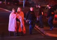 <p>Dos jóvenes envueltas con mantas se alejan del lugar acompañadas por la policía. (Foto: Mike Nelson / EFE). </p>