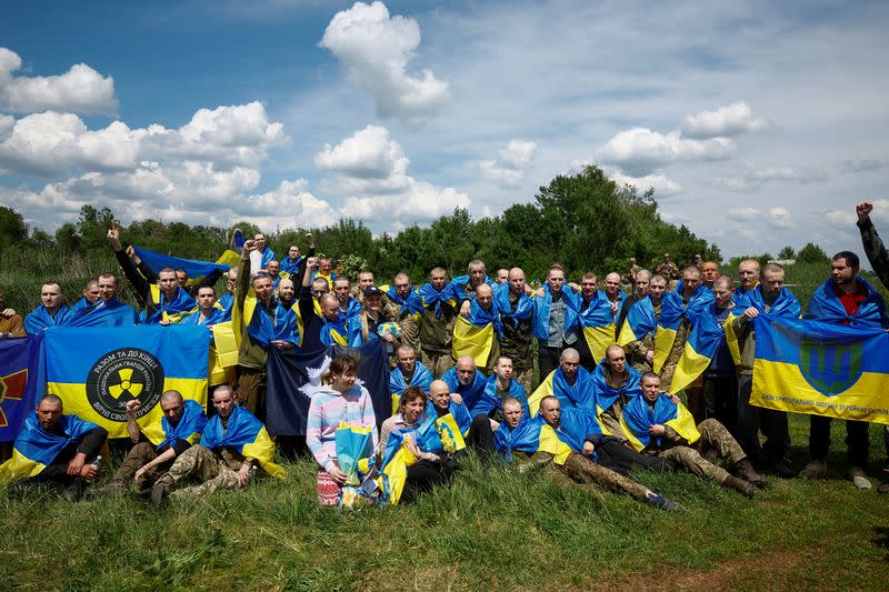 Ukrainian POWs shout slogans while they pose for a picture after a swap at an undisclosed location in Ukraine