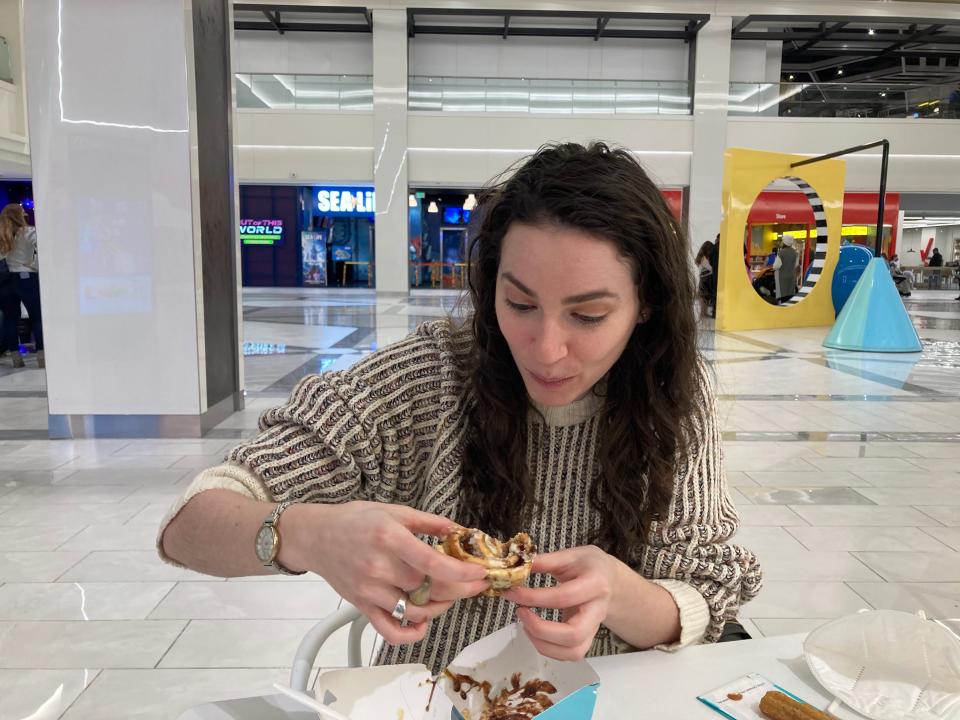 A woman eating Cinnabon.