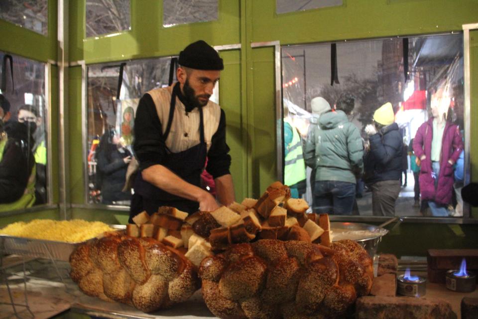 A server at Ayat cuts loaves of challah bread.