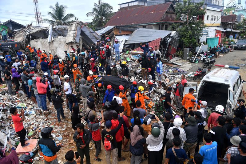 Rescue workers carry a bag with the body a victim following an earthquake in Mamuju